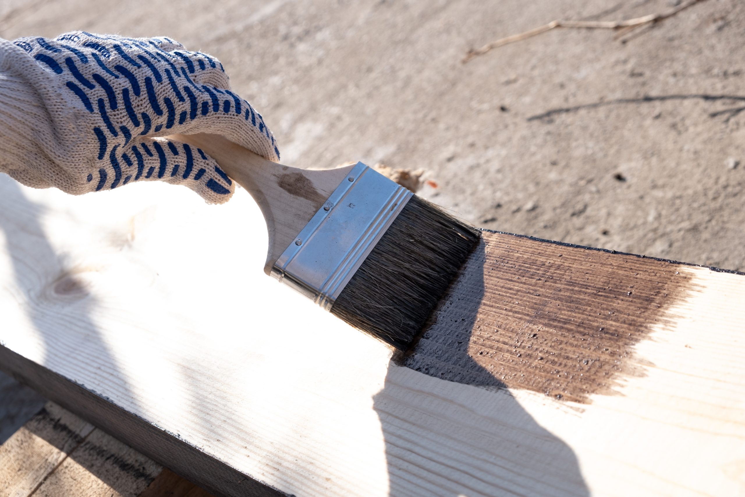 Hand staining a wooden board outdoors